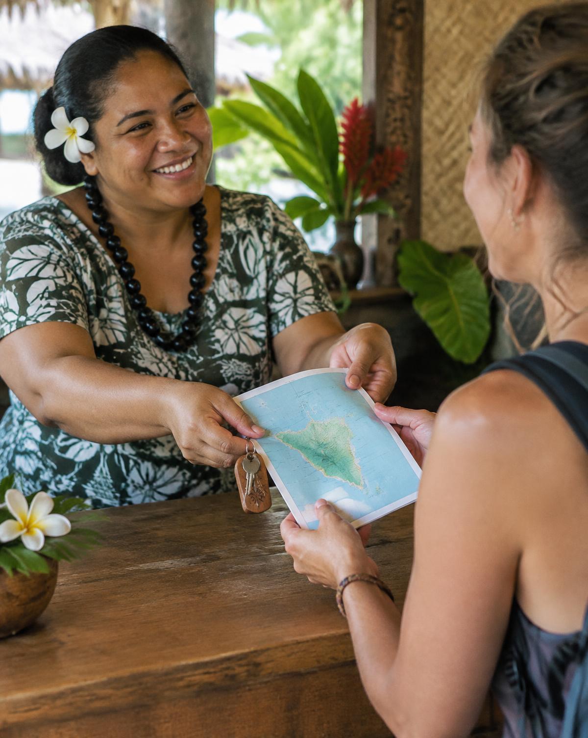 Anfitriona entregando un mapa de la isla y las llaves a una huésped